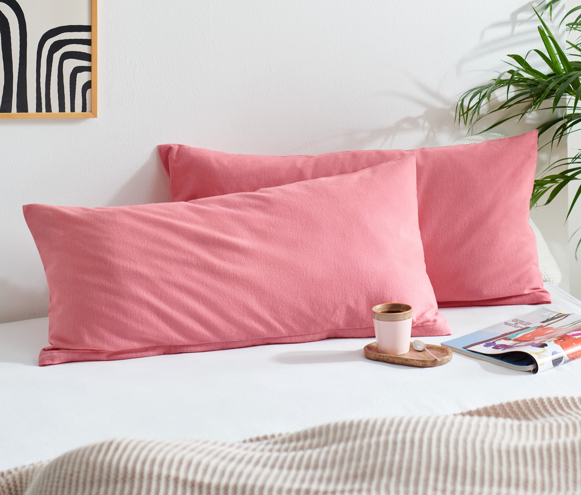 Dva růžové flanelové povlaky na polštáře leží na posteli vedle sebe.