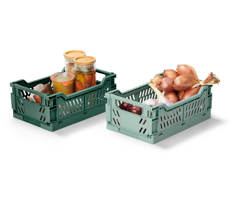 Dvě skládací úložné bedýnky, jedna zelená s naloženými sklenicemi, druhá světle zelená s cibulí a česnekem.