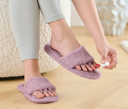 Žena si lakuje nehty na nohou v pantoflích pro lakování nehtů a relaxaci.