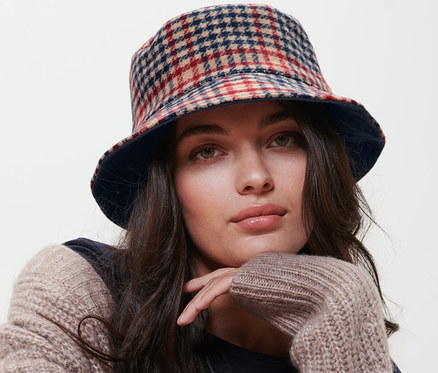 Žena sedí na židli a má na sobě oboustranný klobouk Bucket Hat.