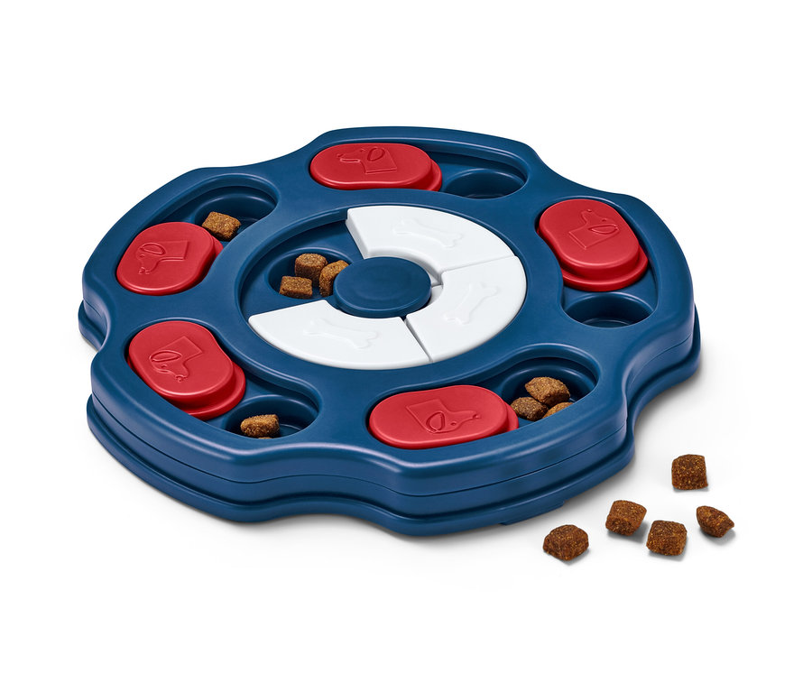 Interaktivní hračka pro psy s modrým podnosem, červenými posuvnými prvky a bílými kostičkami, plná pamlsků.