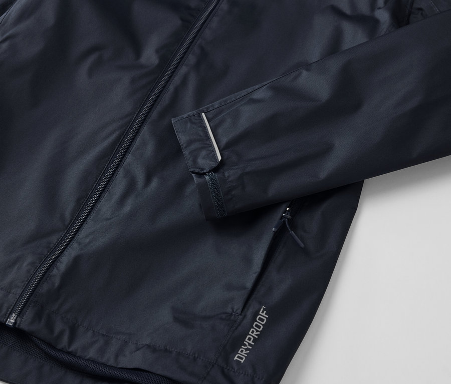 Detail tmavé unisexové bundy do deště s reflexním proužkem na rukávu.