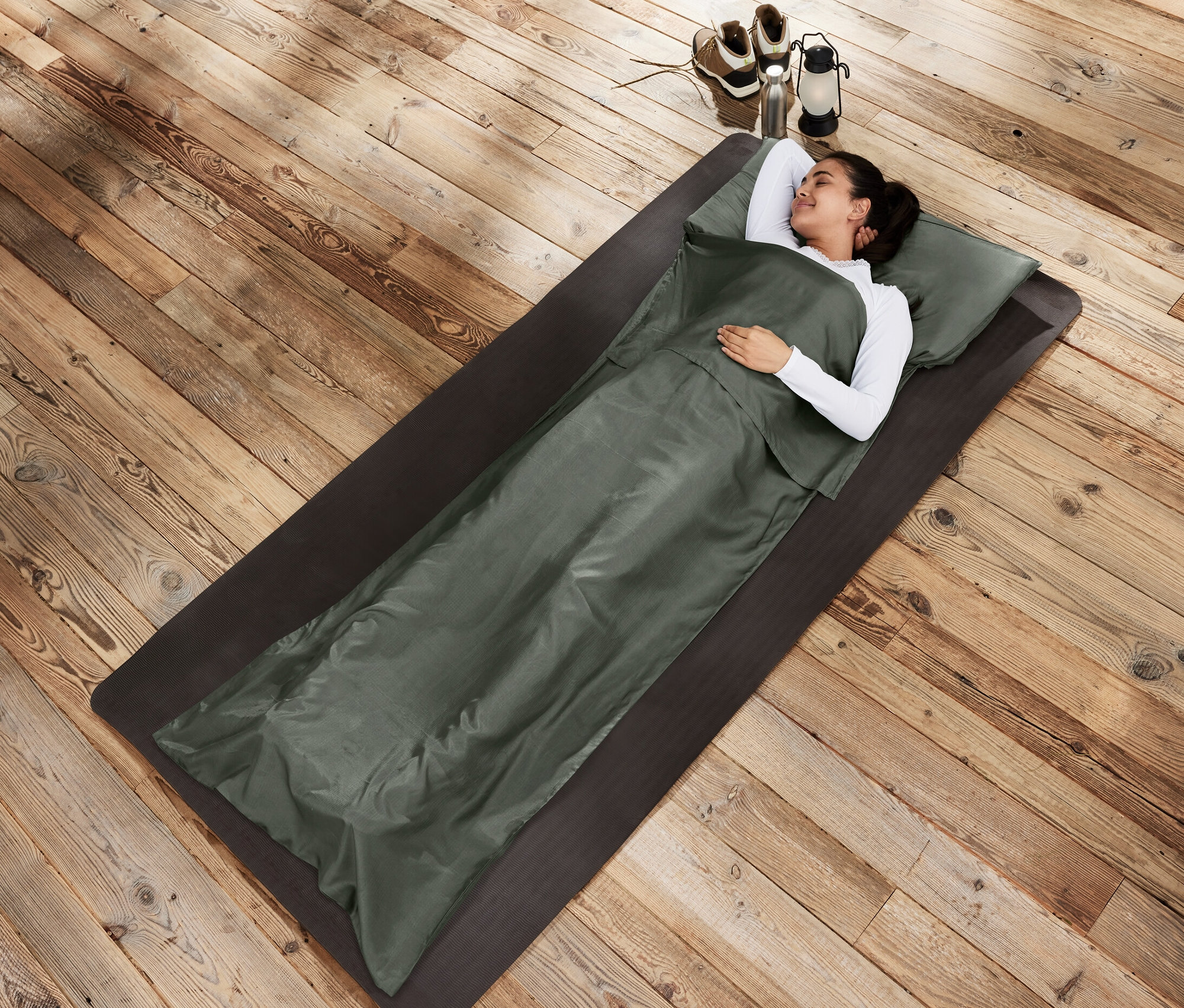 Žena leží na podložce ve spacáku Hedvábná vložka do spacího pytle.