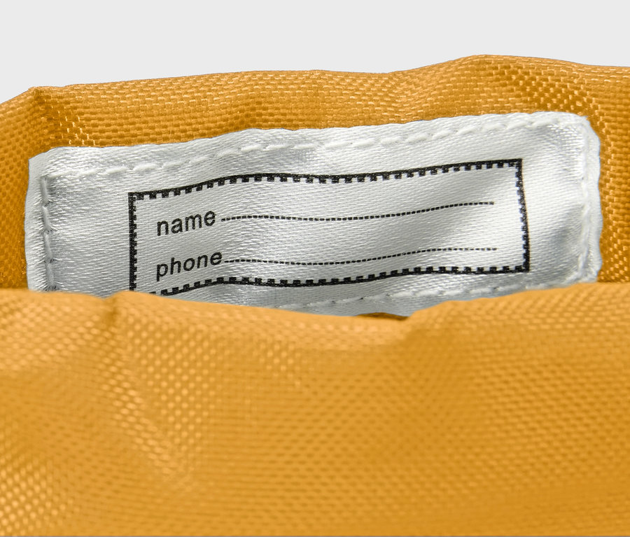 Detail dětských gumových holínek, žlutá barva, s bílou nášivkou na jméno a telefonní číslo.