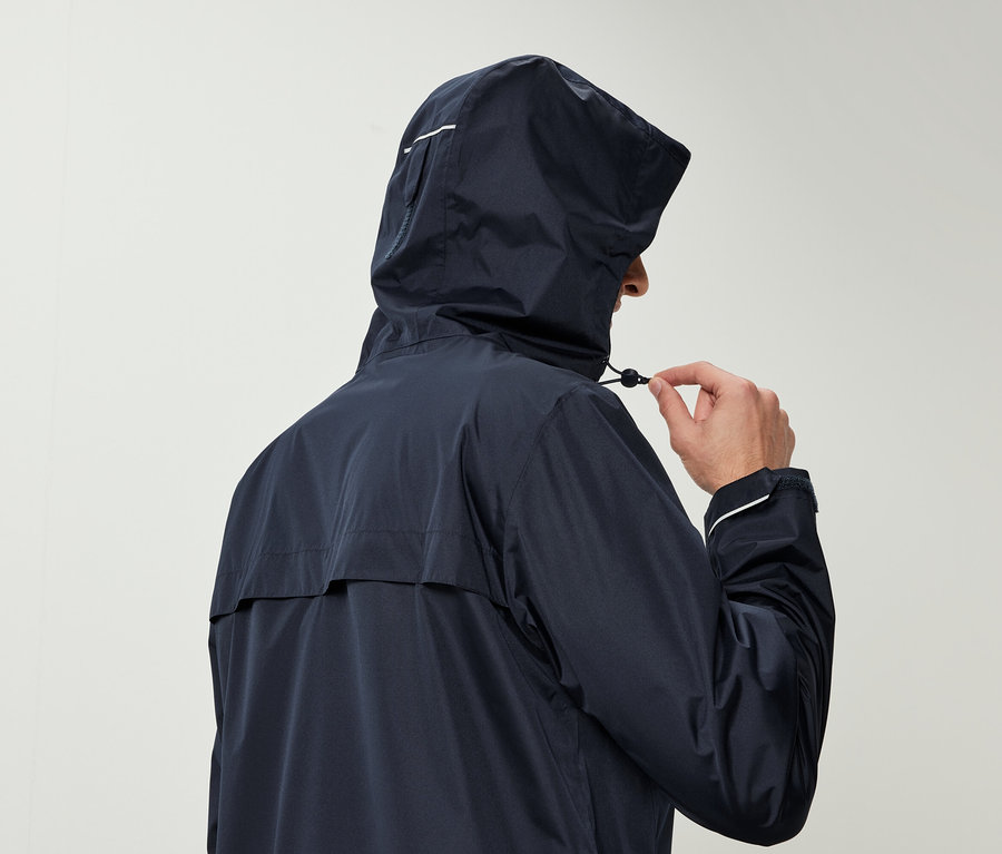 Muž v tmavě modré bundě s kapucí stahuje šňůrku na kapuci.