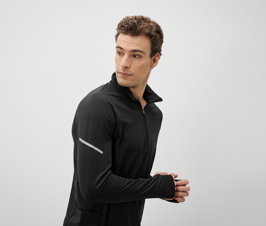 Muž v černém sportovním topu se dívá přes rameno.