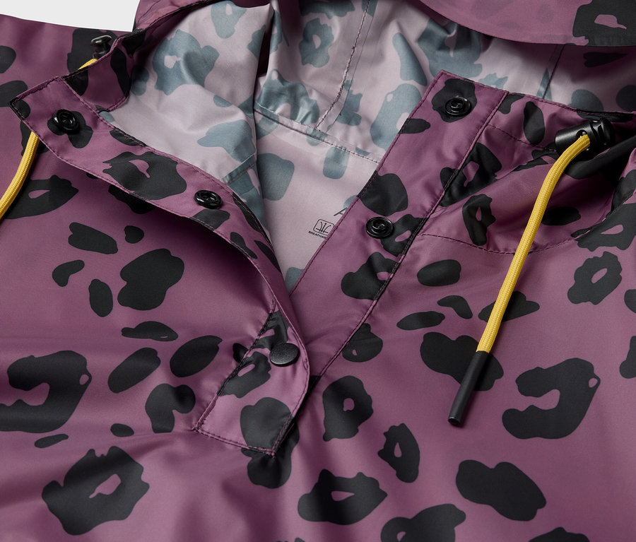 Detail fialové bundy s kapucí a černým zvířecím vzorem.