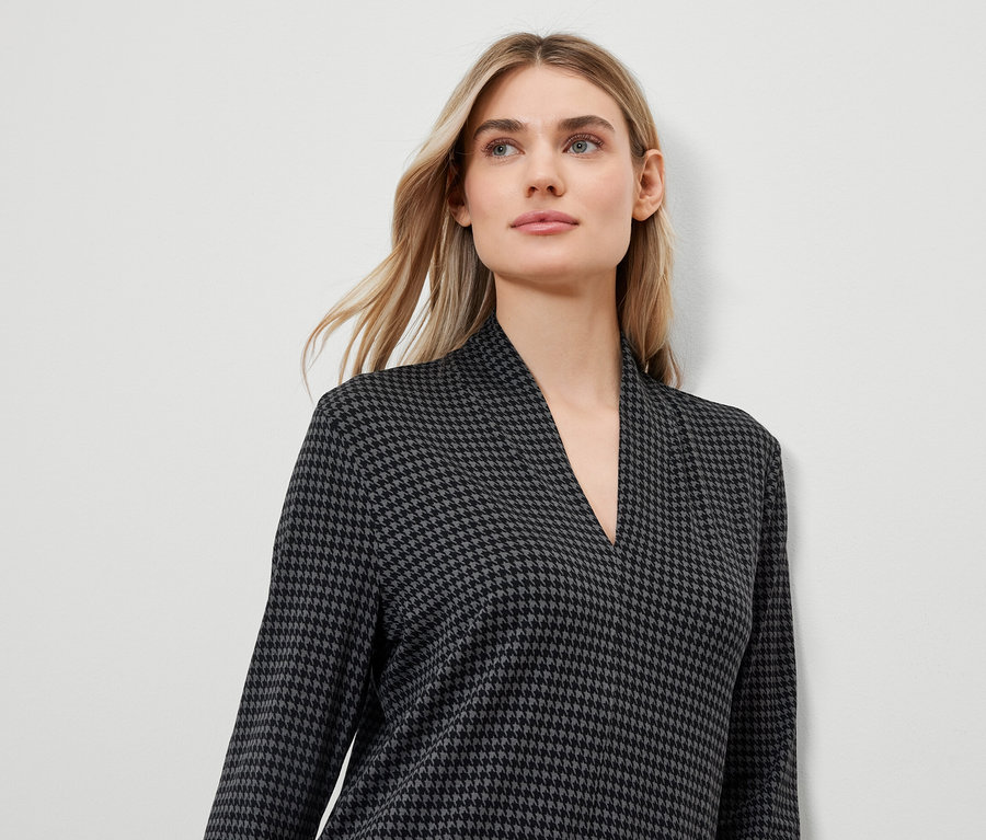 Blondýna v šatech se vzorem kohoutí stopy s výstřihem do V.