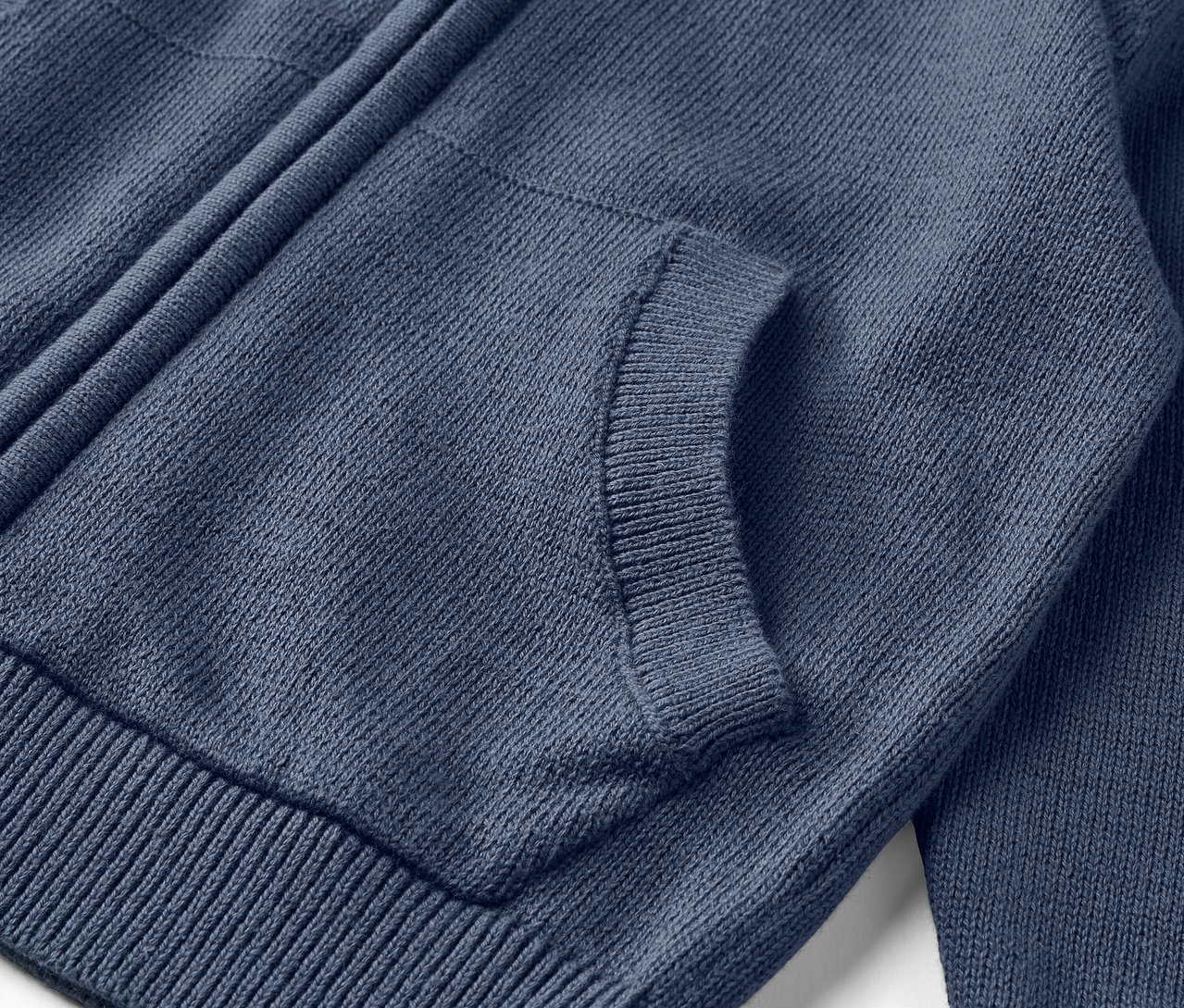 Detail modrého dívčího pleteného svetru se zipem a kapsou.