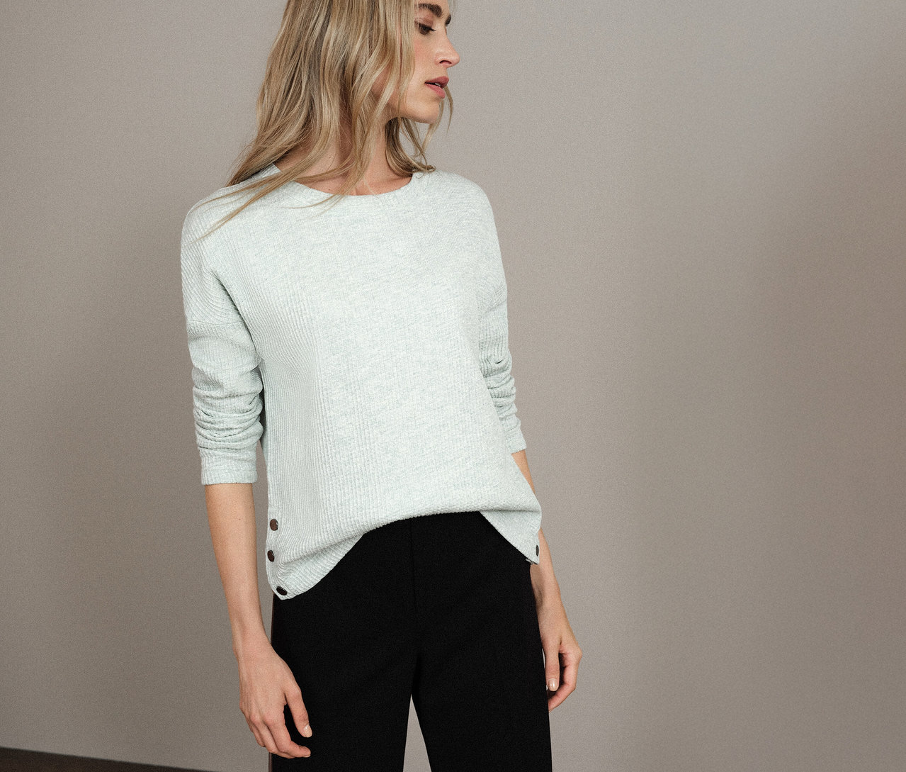 Žena má na sobě světle modré strukturované tričko Street One a černé kalhoty.