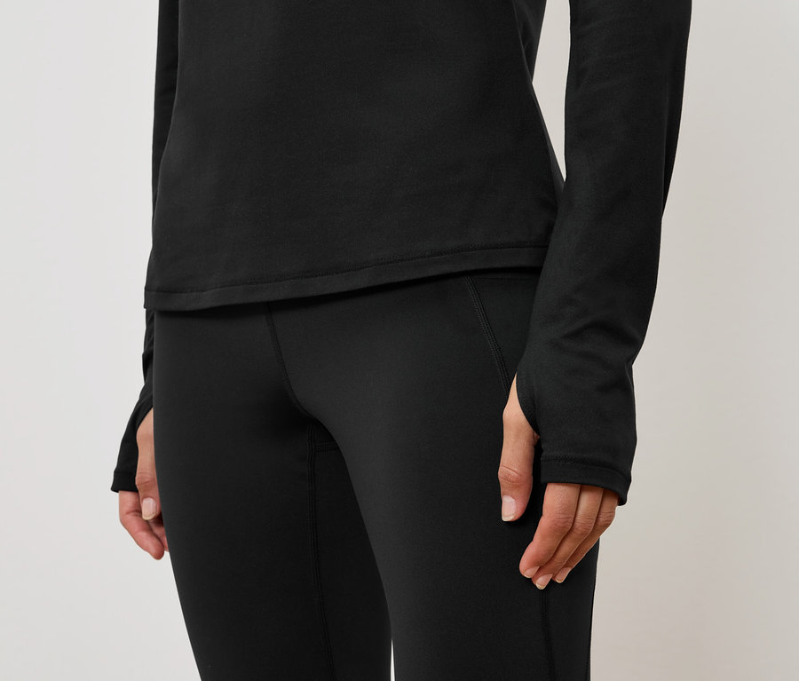 Detail dámského černého sportovního outfitu s dlouhým rukávem a legínami.