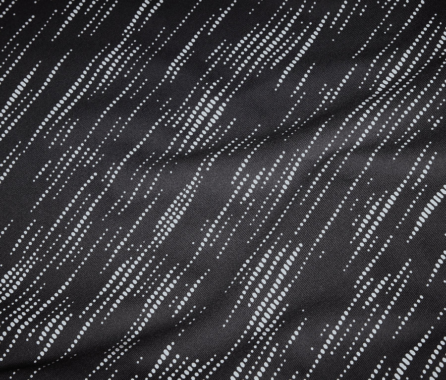 Detailní záběr na černou látku s diagonálními bílými tečkovanými liniemi.