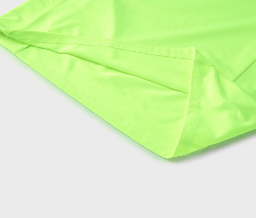Detailní záběr světle zelené látky se švy na okrajích, ležící na bílém povrchu.