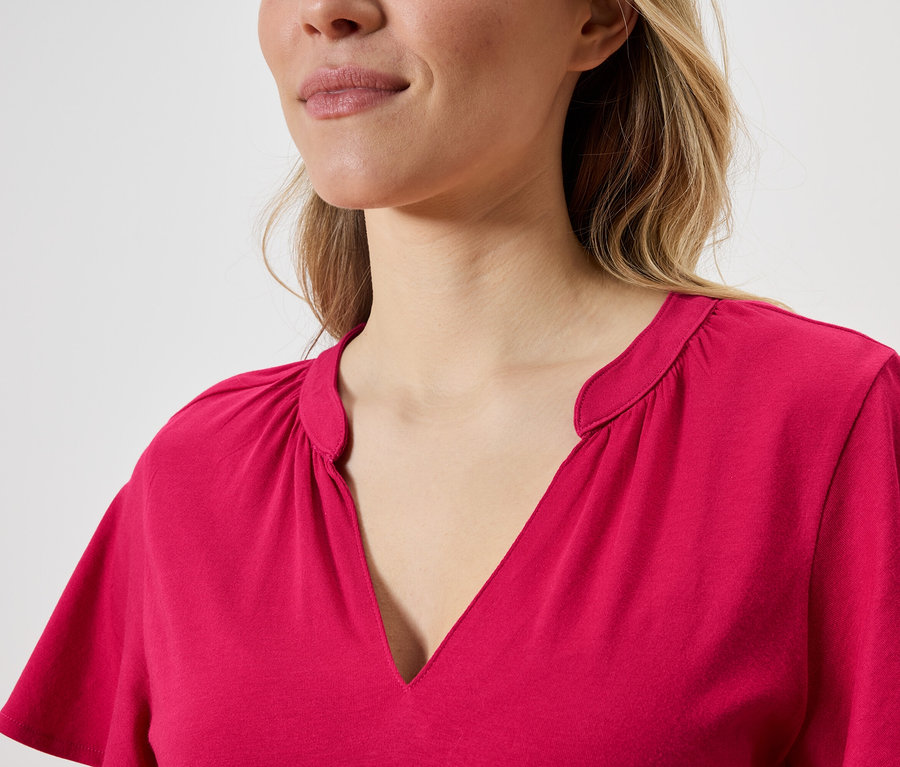 Detailní záběr ženy s blond vlasy v růžovém topu s výstřihem do V.