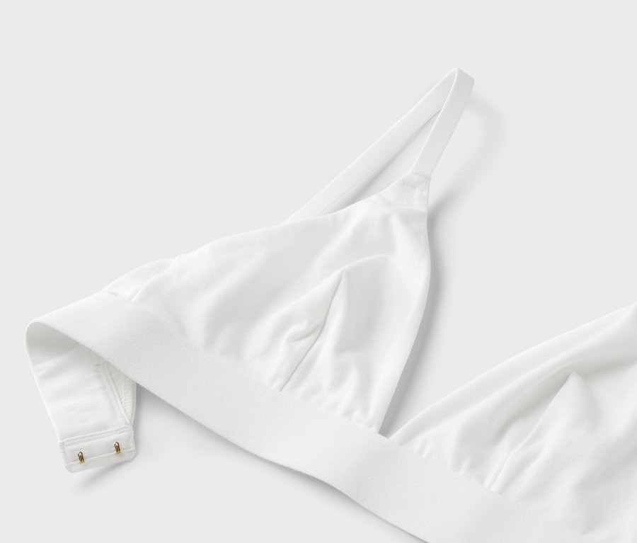 Detailní záběr bílé podprsenky s tenkými ramínky na bílém pozadí.