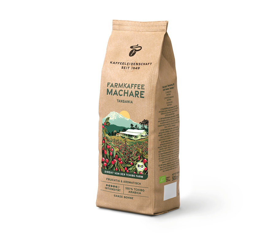 Stojící hnědé balení kávy Farmkaffee Machare z Tanzanie, s ilustrací kávové plantáže, hory a domu. Obsahuje 500g celých zrn.