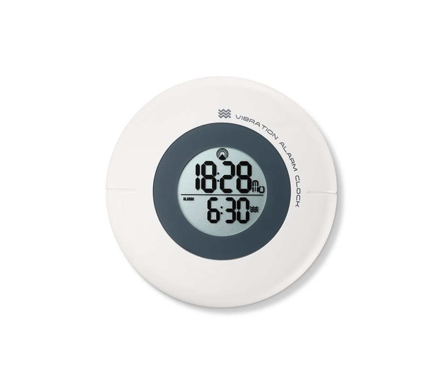 Detailní záběr na Vibrační budík řízený rádiovým signálem, který ukazuje čas 18:28 a nastavený budík na 6:30.