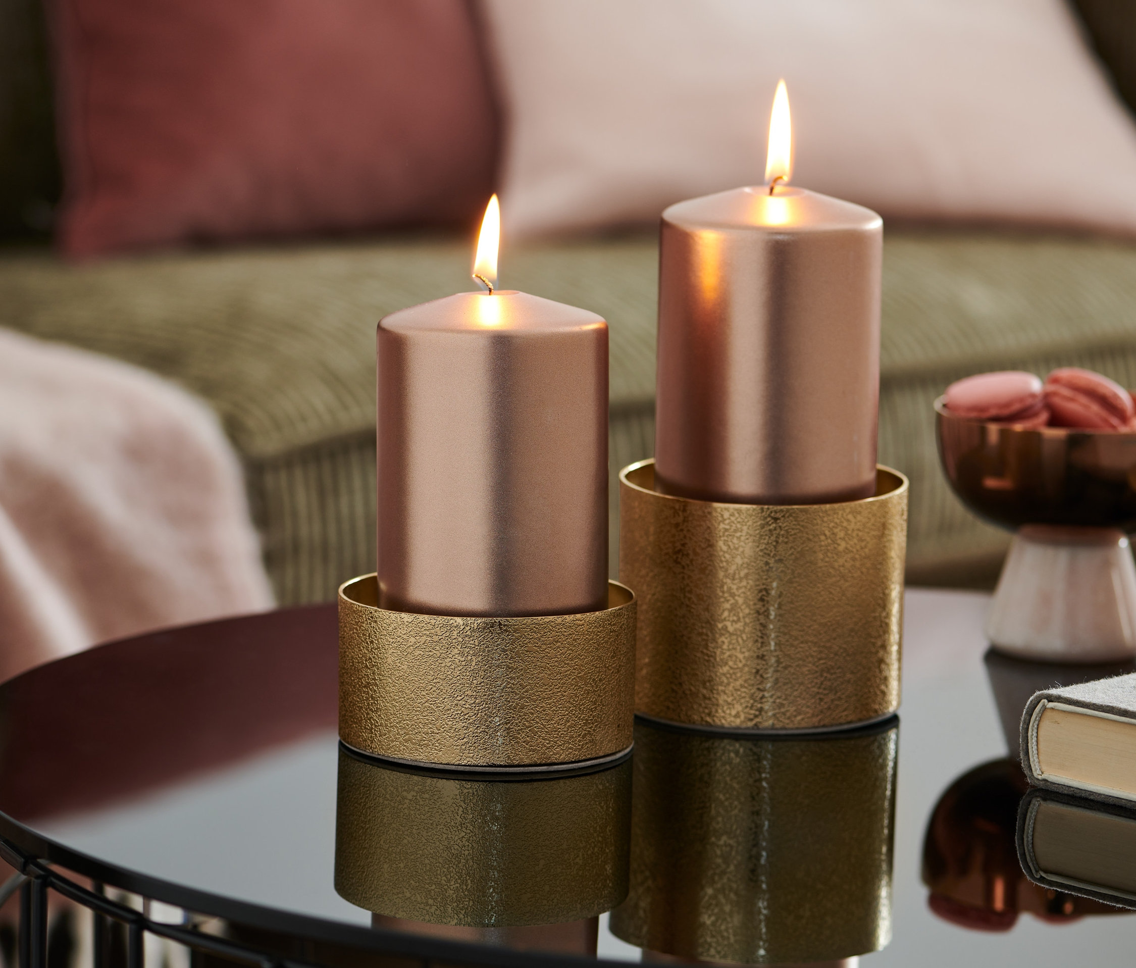 Dvě hořící růžové svíčky stojí na zlatých stojanech na lesklém stolku. Stojánky na svíčky, 2 ks.
