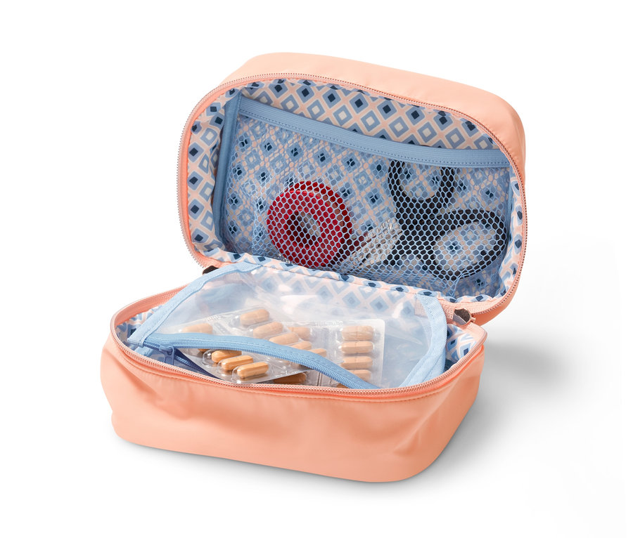 Otevřená broskvová taštička na léky s léky, nůžkami a červenou páskou uvnitř.