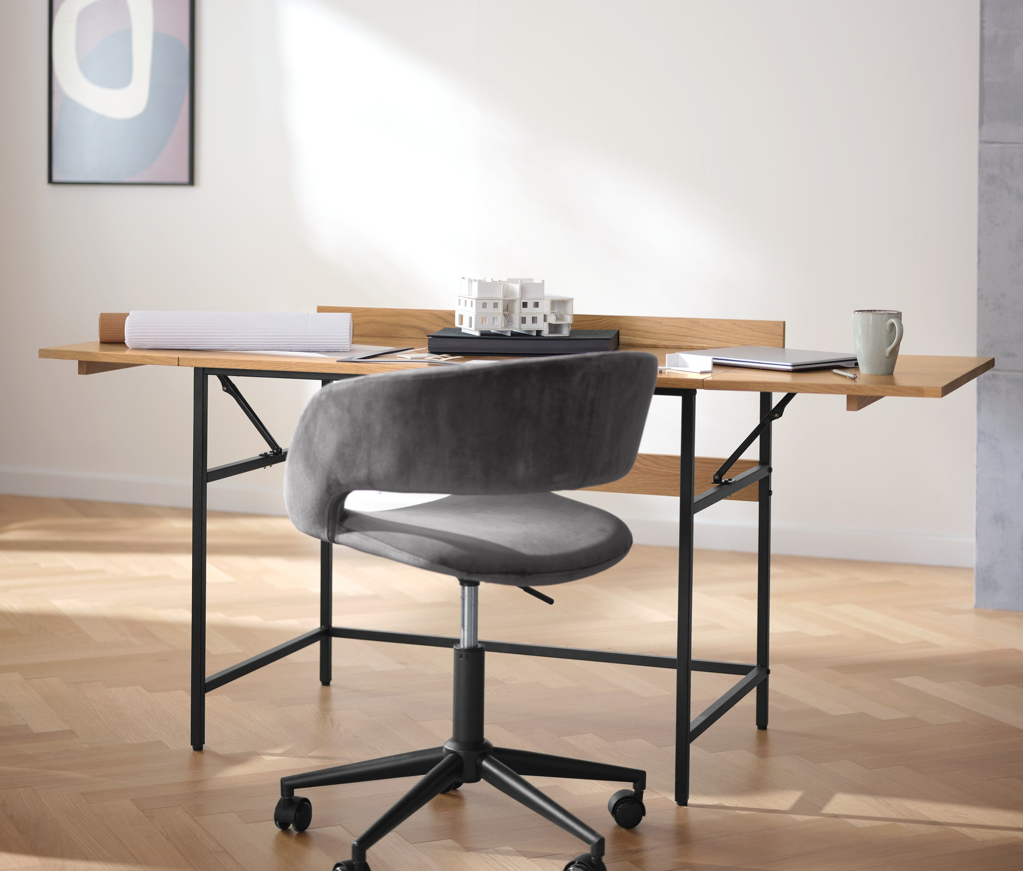 Černý box na pěstování stojí vedle kovové stolní lampy a rozkládacího pracovního stolu z masivního dřeva.