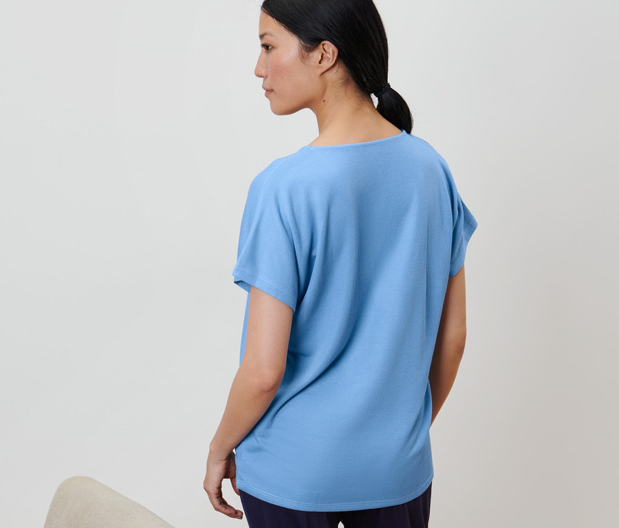 Žena má na sobě světle modré strukturované tričko.