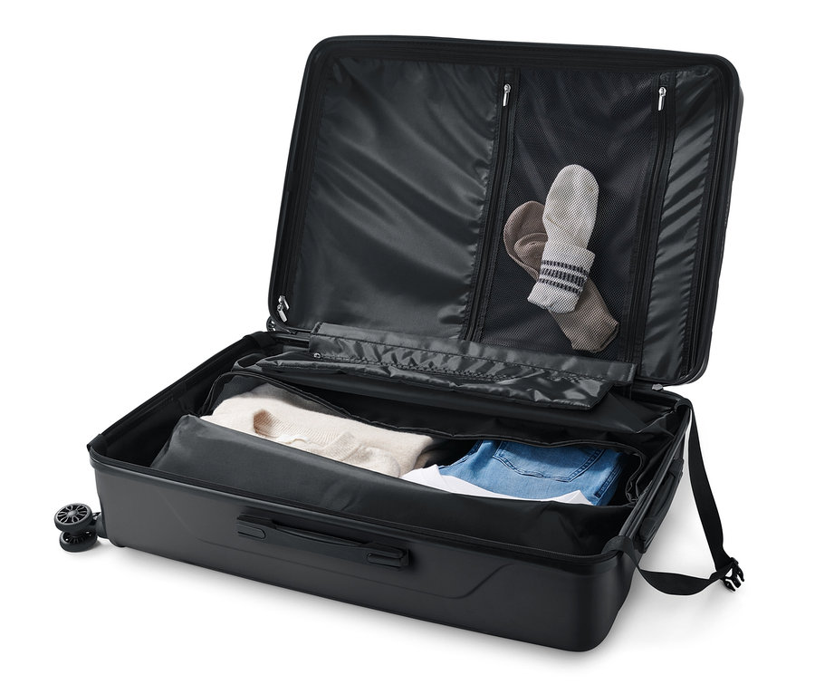 Otevřený velký kufr z tvrdé skořepiny s oblečením uvnitř.