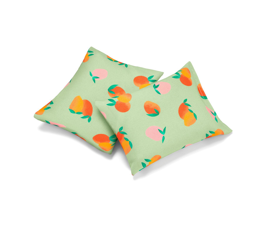 Dva osvěžující polštářky s potiskem broskví na světle zeleném pozadí.