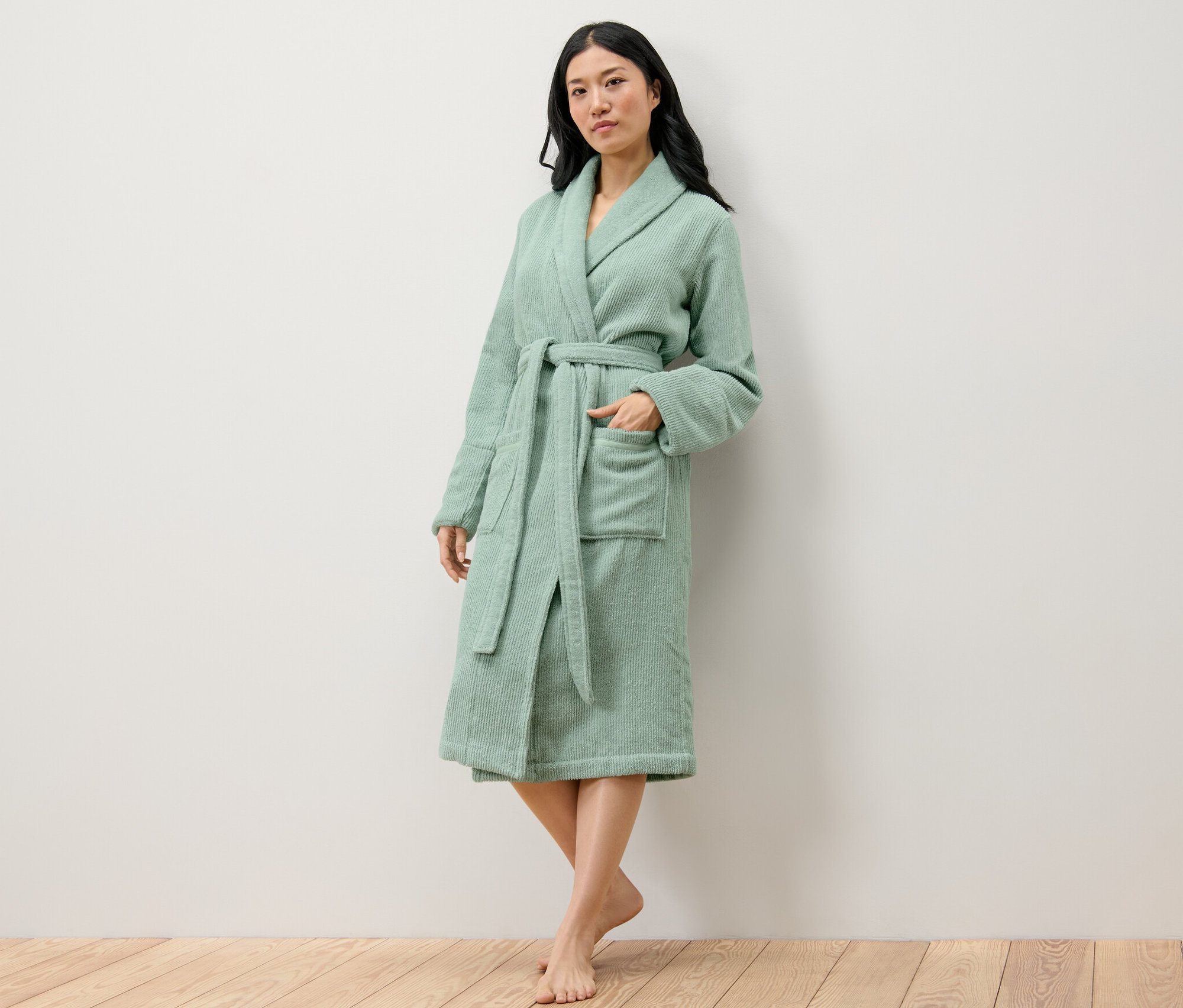 Žena pózuje v zeleném dámském županu.