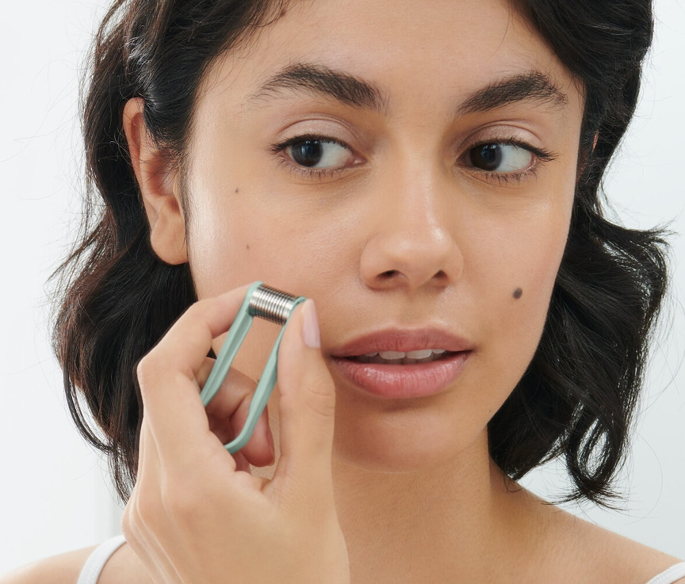 Žena používá ruční mini odstraňovač chloupků na obličeji.