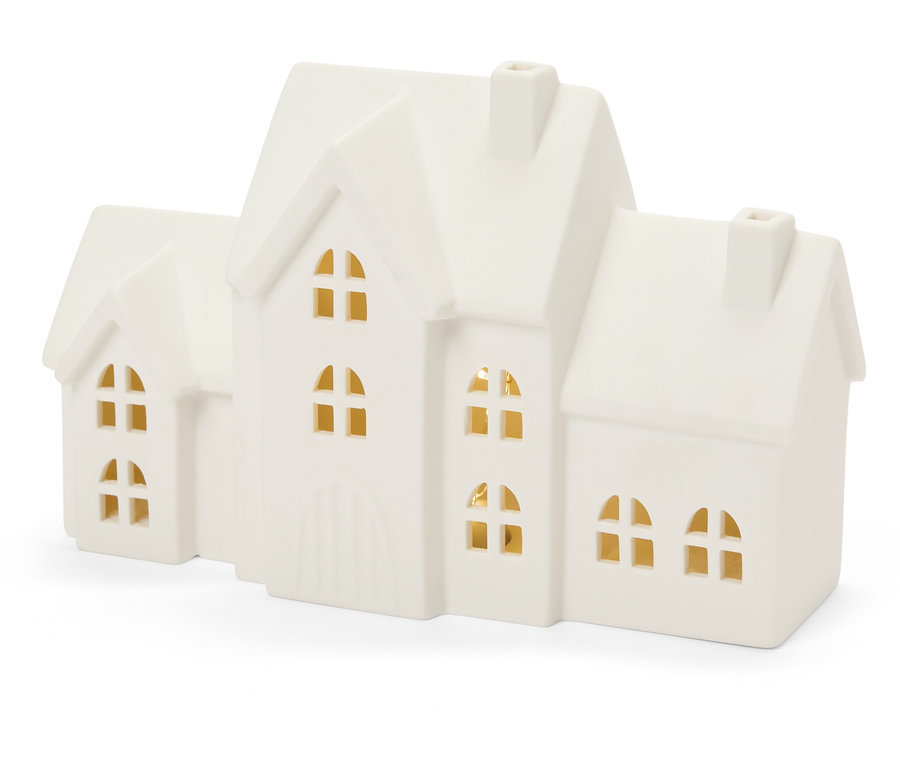 Dekorativní porcelánový domeček se světly ve oknech.