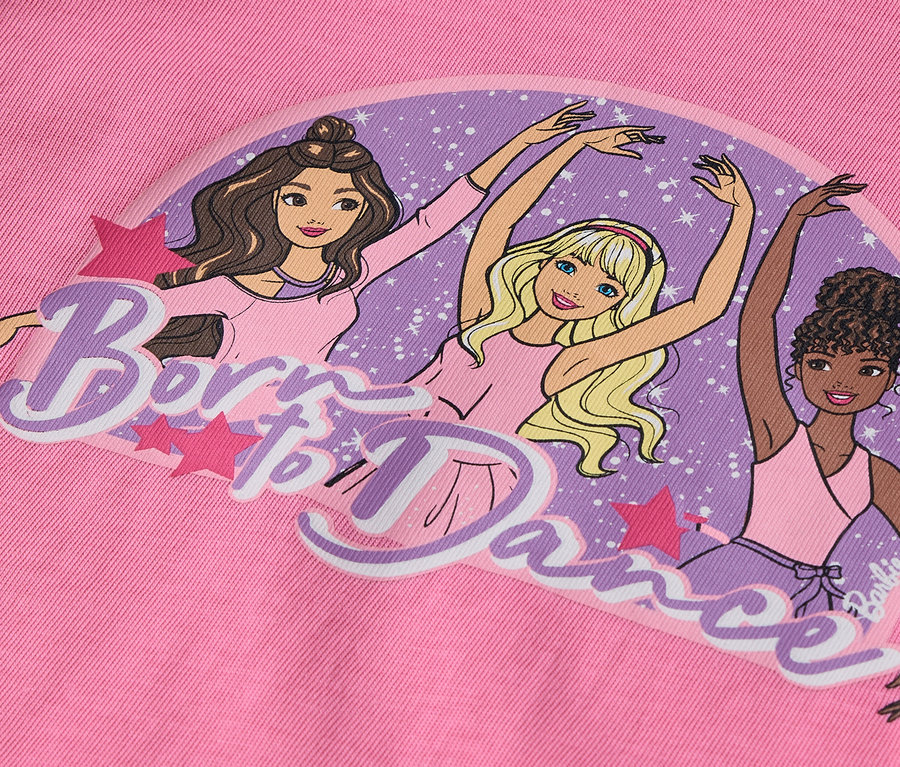 Na růžovém pozadí je obrázek tří postaviček Barbie v baletních pozicích s nápisem "Born to Dance".