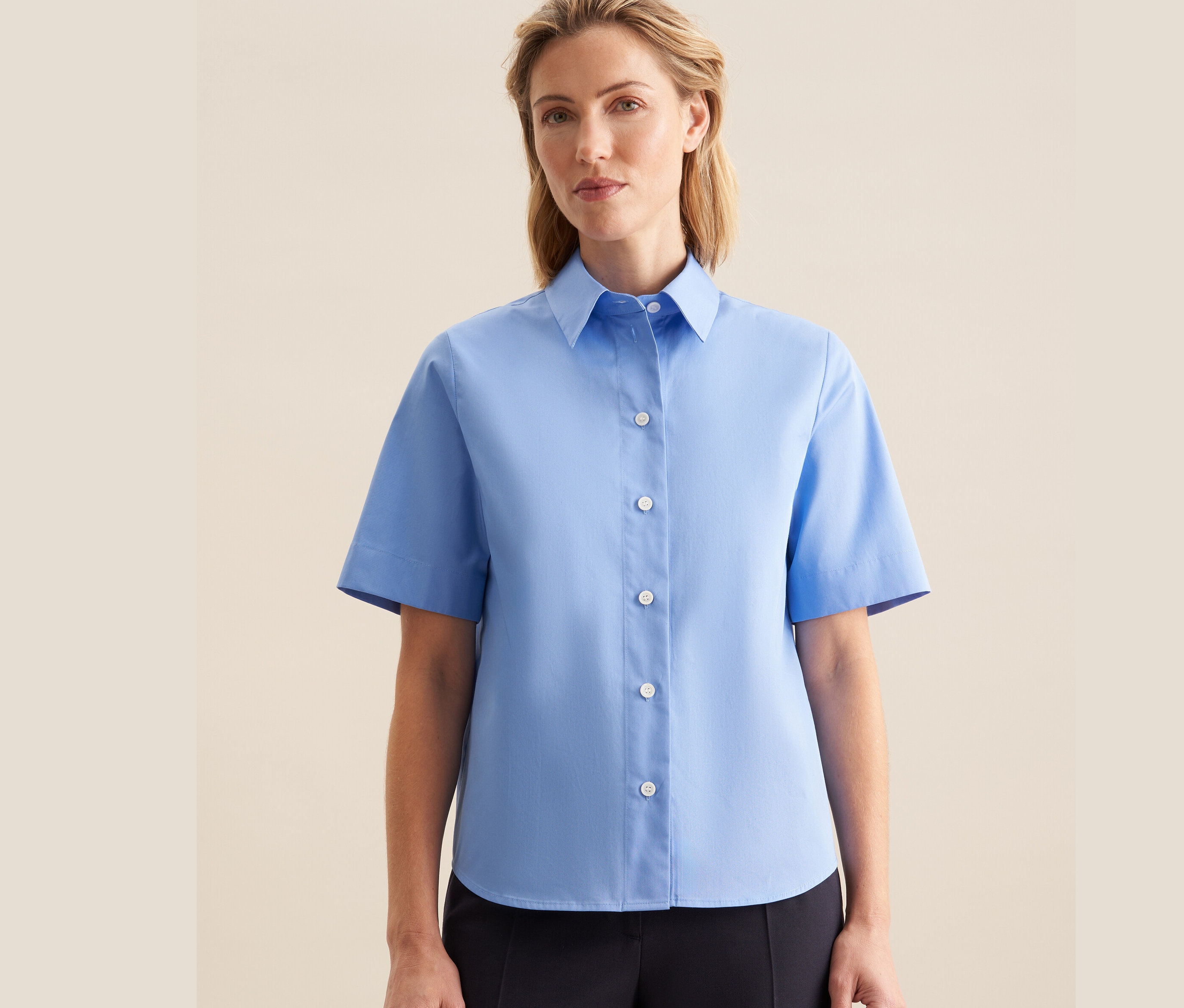 Žena má na sobě světle modrou halenku s krátkým rukávem Seidensticker.