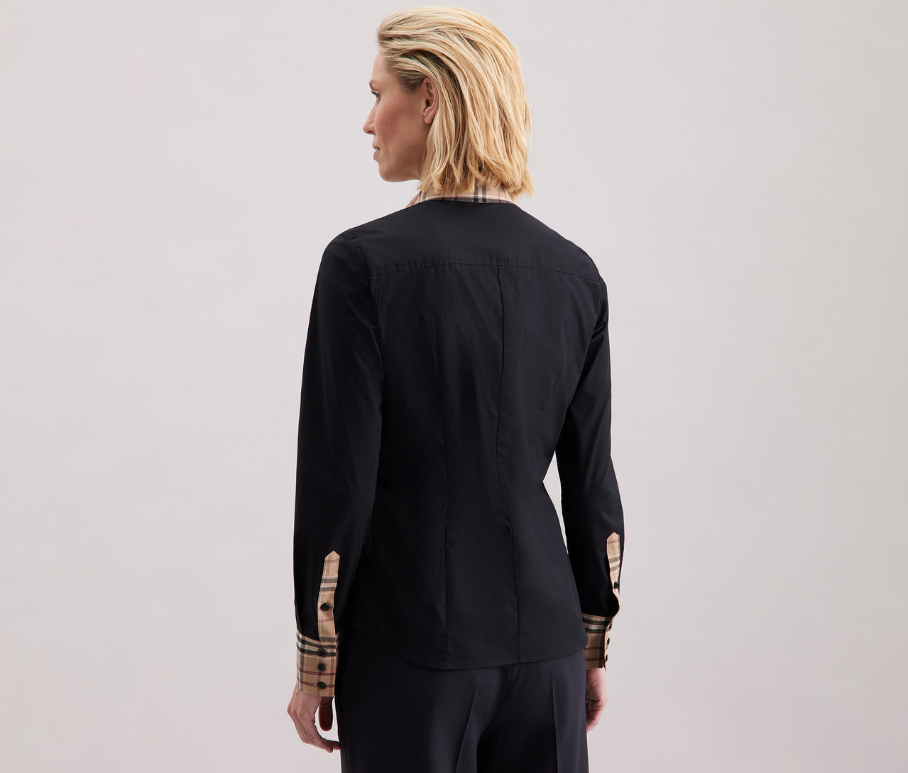 Žena má na sobě popelínovou halenku s kostkovaným detailem Seidensticker.