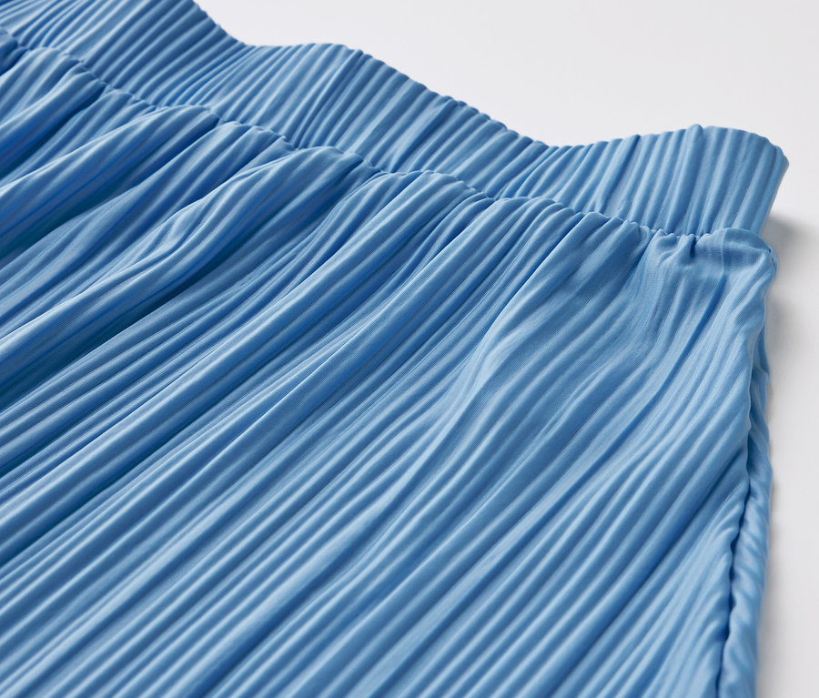 Detail modré plisované sukně.