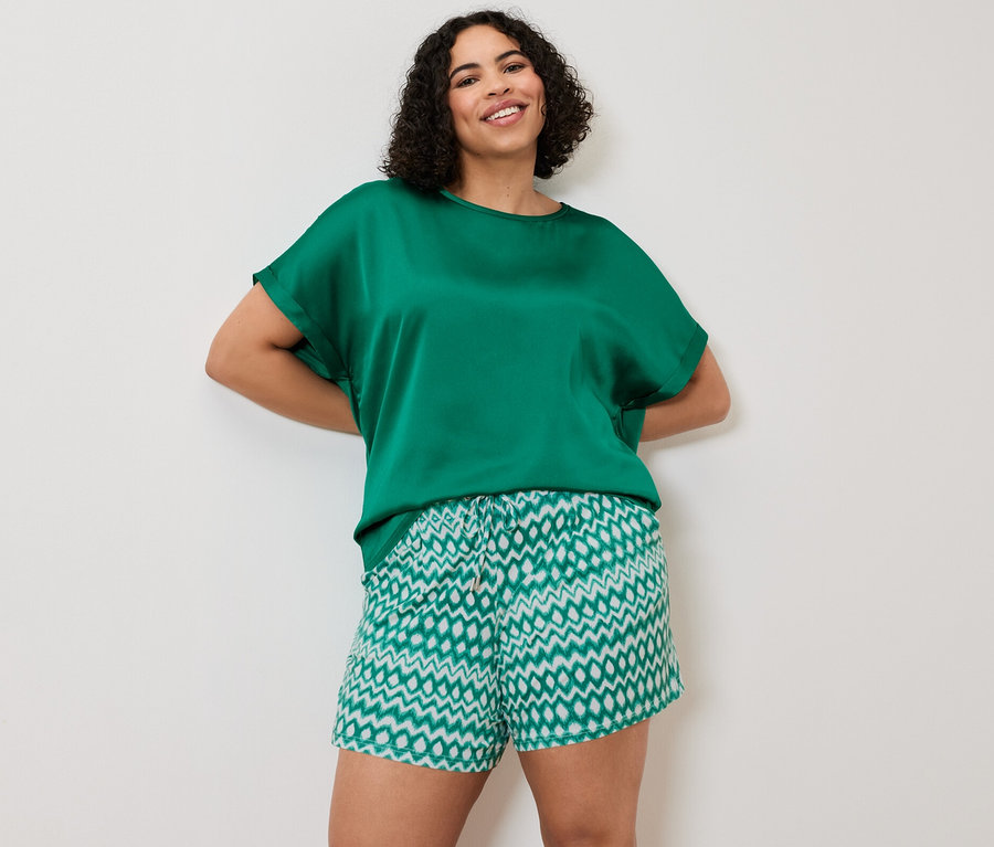 Žena pózuje v halence modrozelené barvy a v žerzejových šortkách, 2 ks.