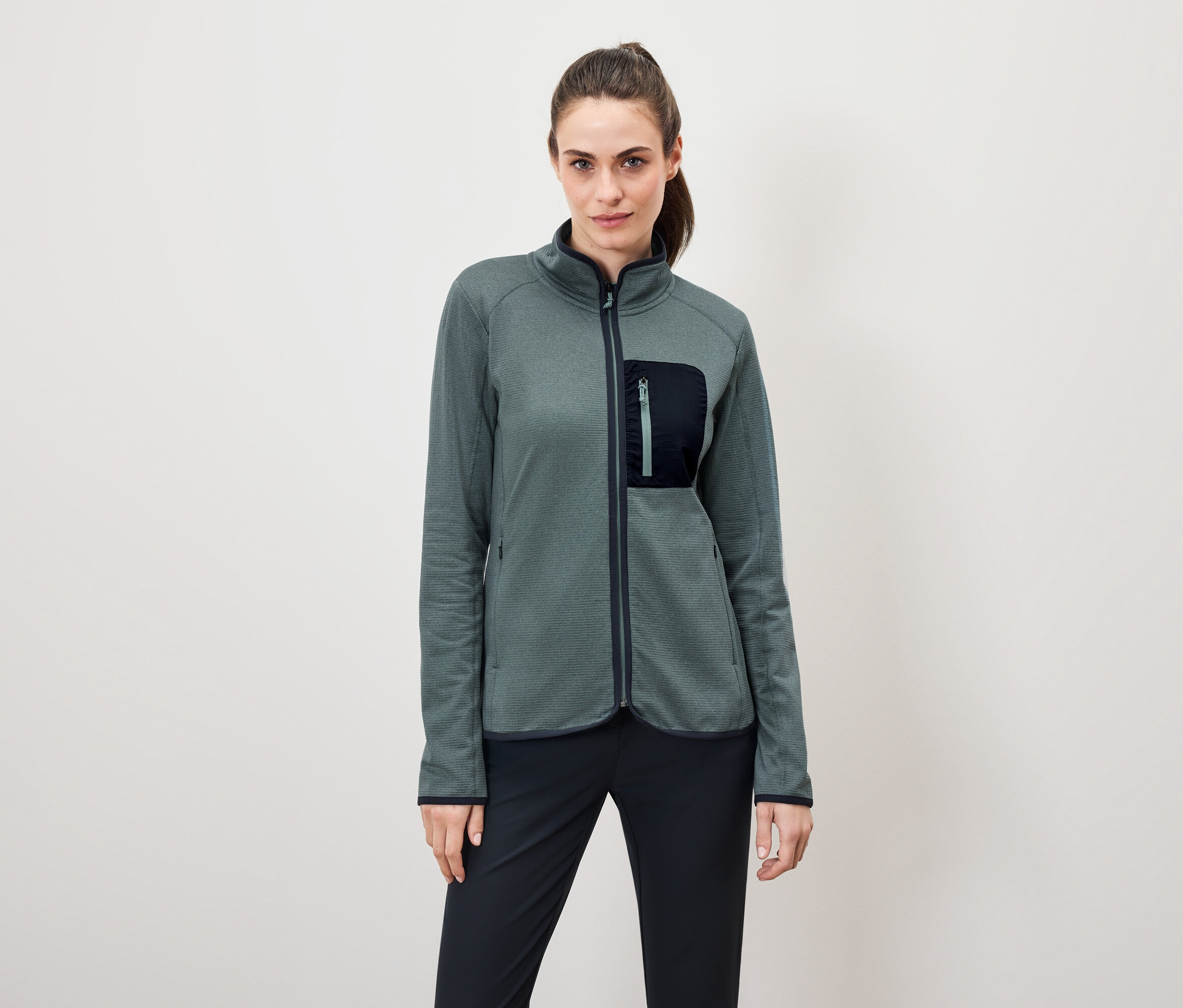 Žena má na sobě zelenou fleecovou bundu s černými kalhotami.