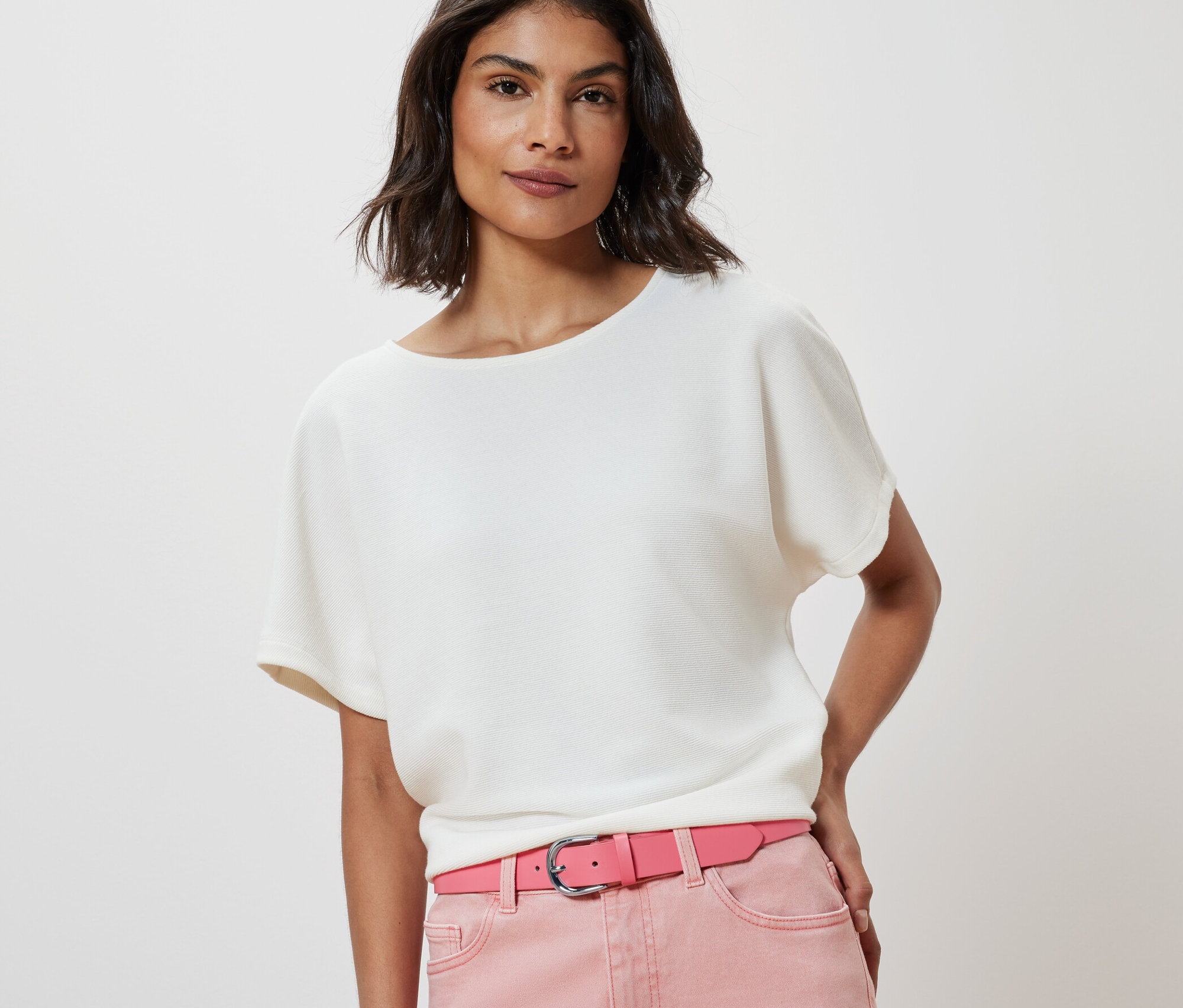 Žena má na sobě bílou halenku a růžový opasek.