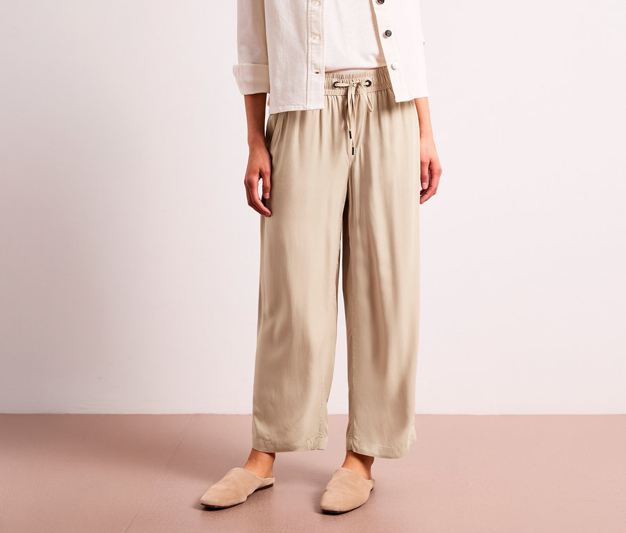 Osoba v béžových 7/8 kalhotách culottes Street One, bílé košili a béžových pantoflích.
