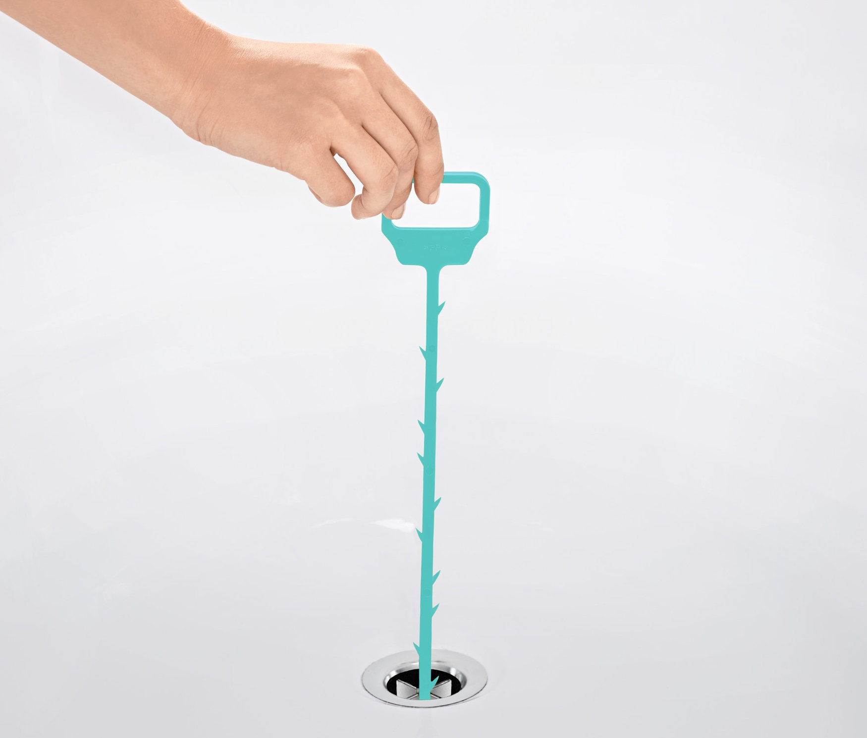 Ruka vkládá modrý čistič odpadu do odtoku umyvadla.