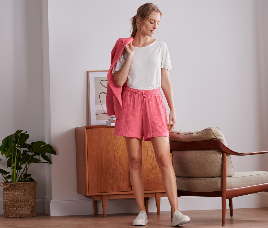 Žena stojí a má na sobě mušelínové šortky a sako.