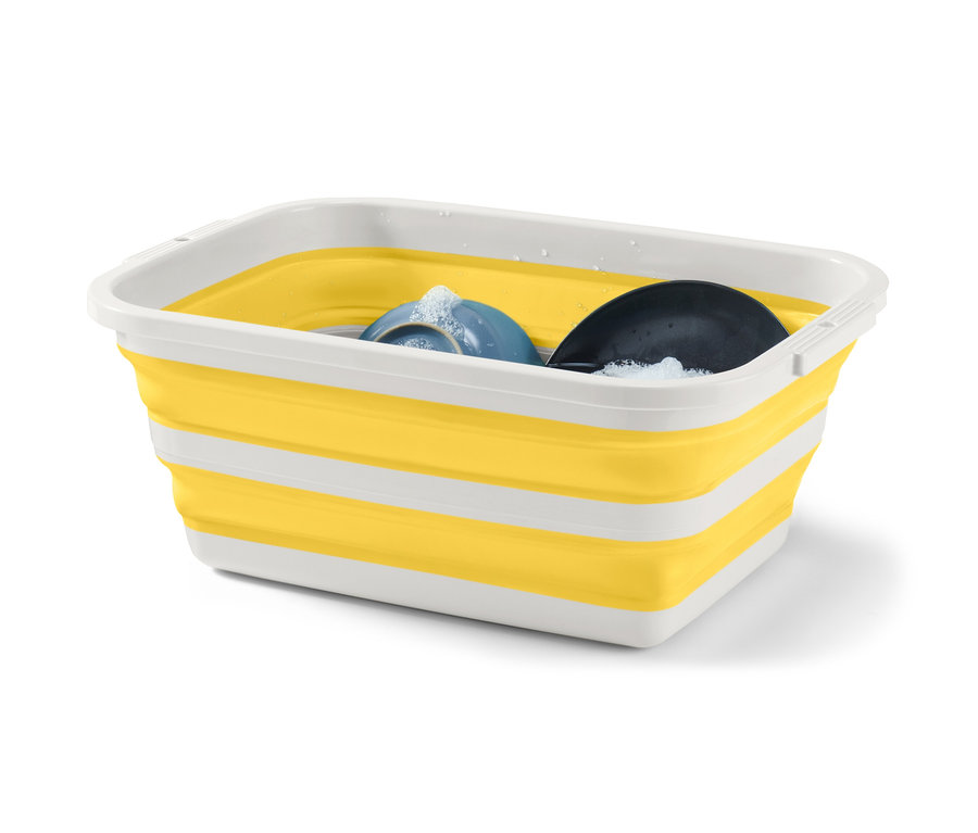 Skládací koš na prádlo žluté a bílé barvy s mycími prostředky a nádobím uvnitř.