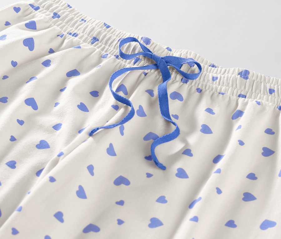 Detail pyžamových kalhot se srdíčky a modrou stahovací šňůrkou.