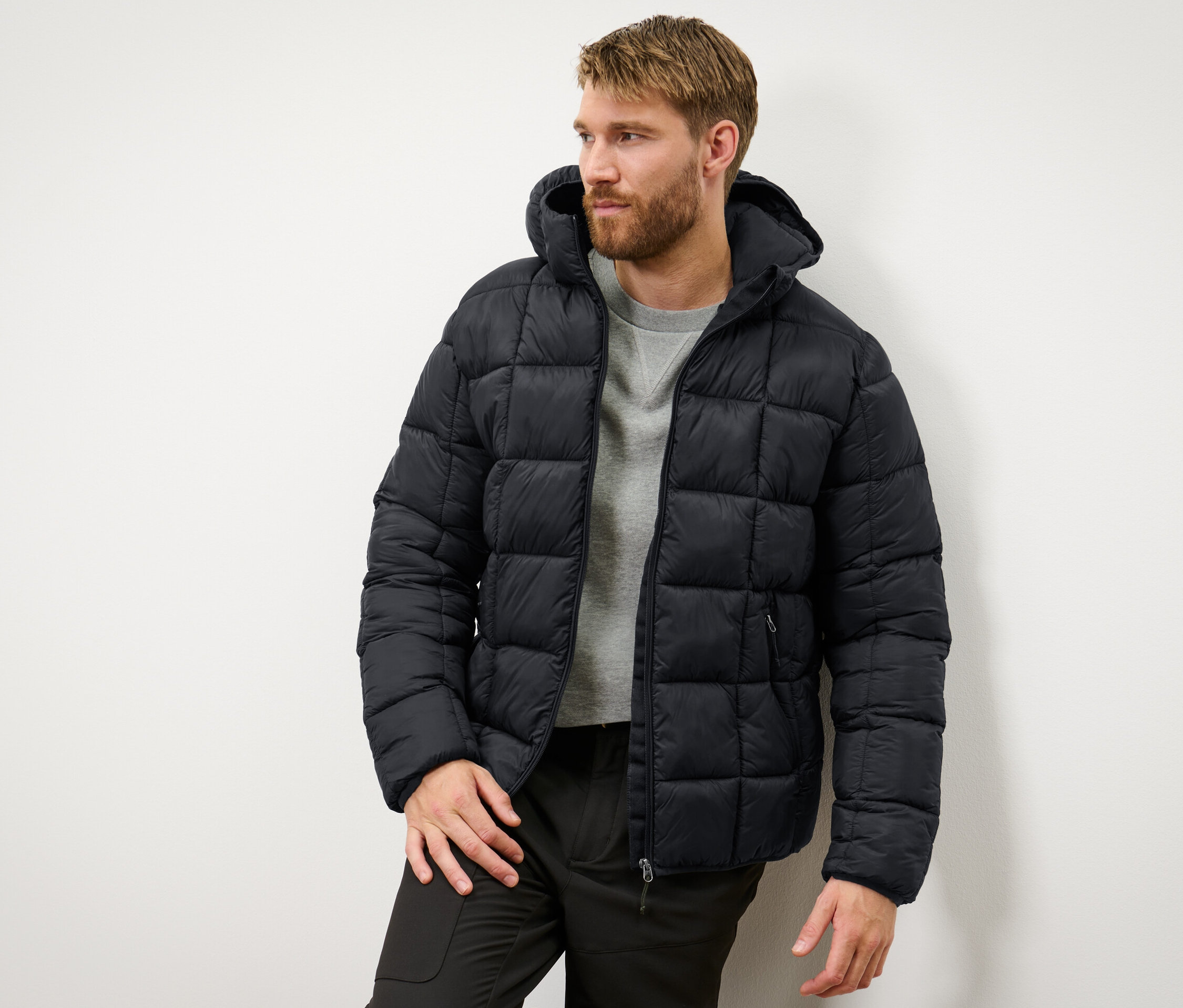 Muž má na sobě černou prošívanou bundu.