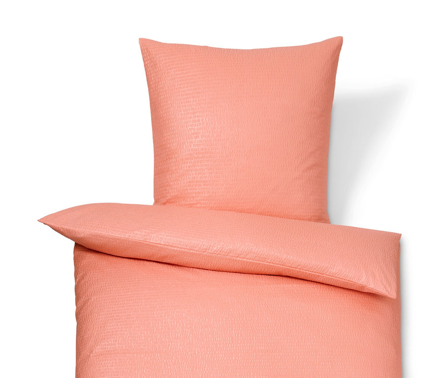 Korálové krepové povlečení standardní a nadměrné velikosti leží na bílém pozadí.