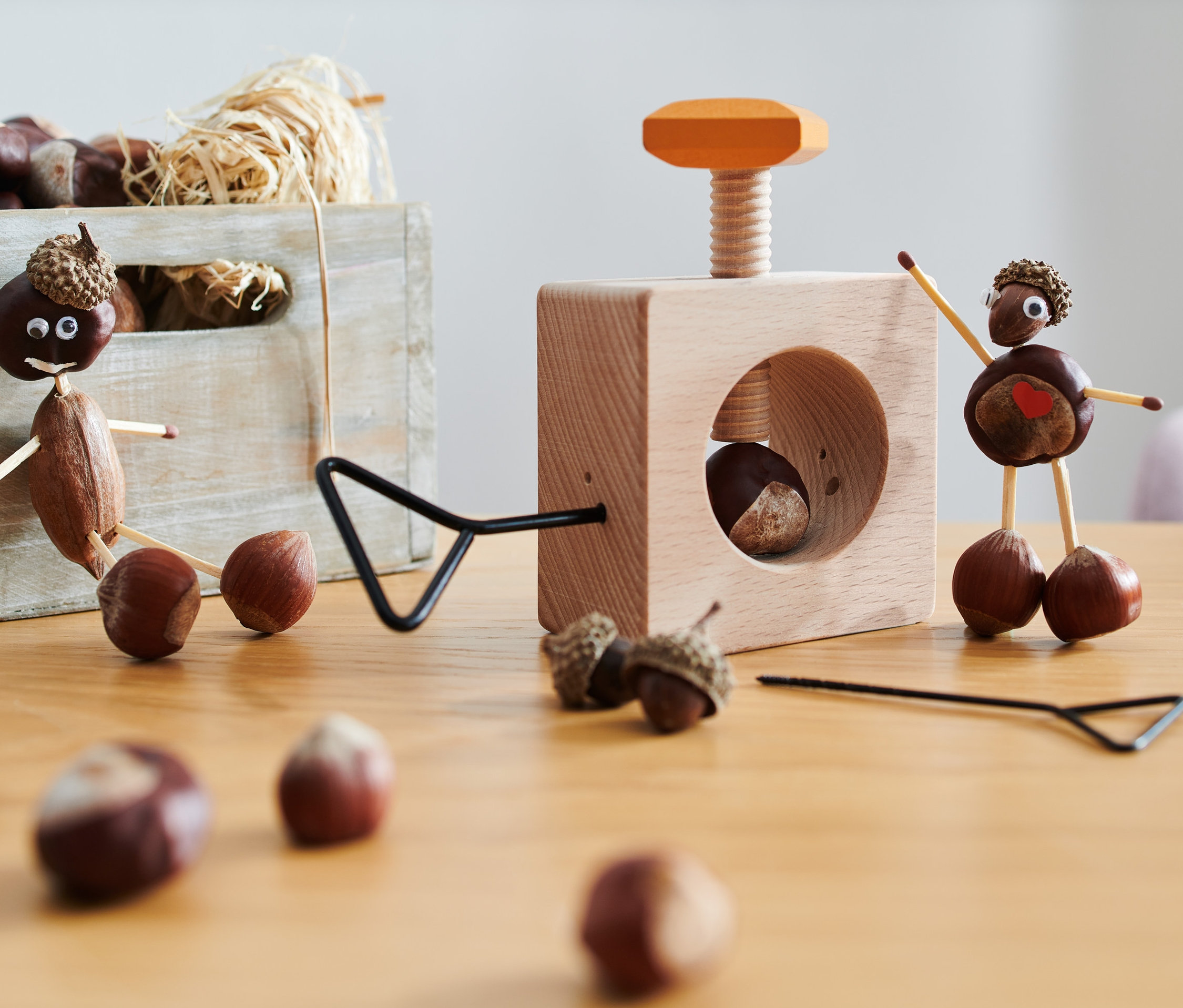 Dva kaštanoví panáčci a vrták na kaštany a louskáček 2 v 1 na stole.