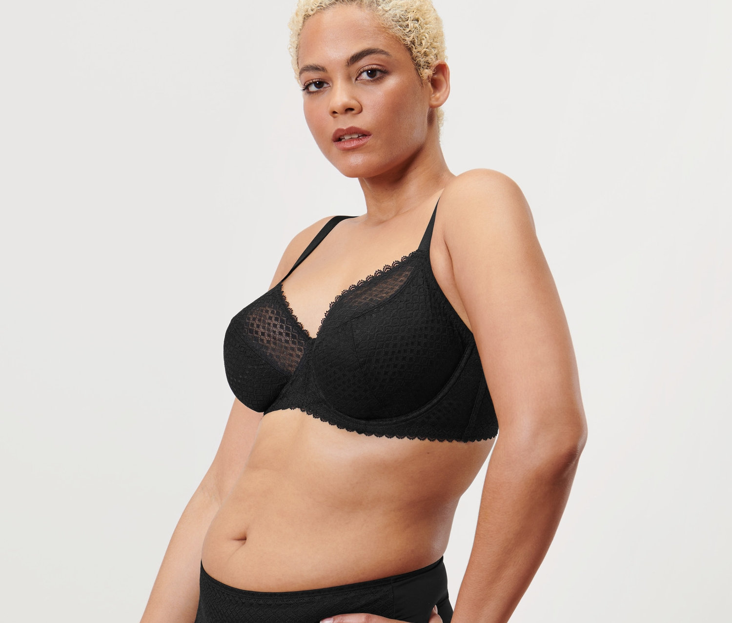 Žena pózuje v černé podprsence s kosticemi.