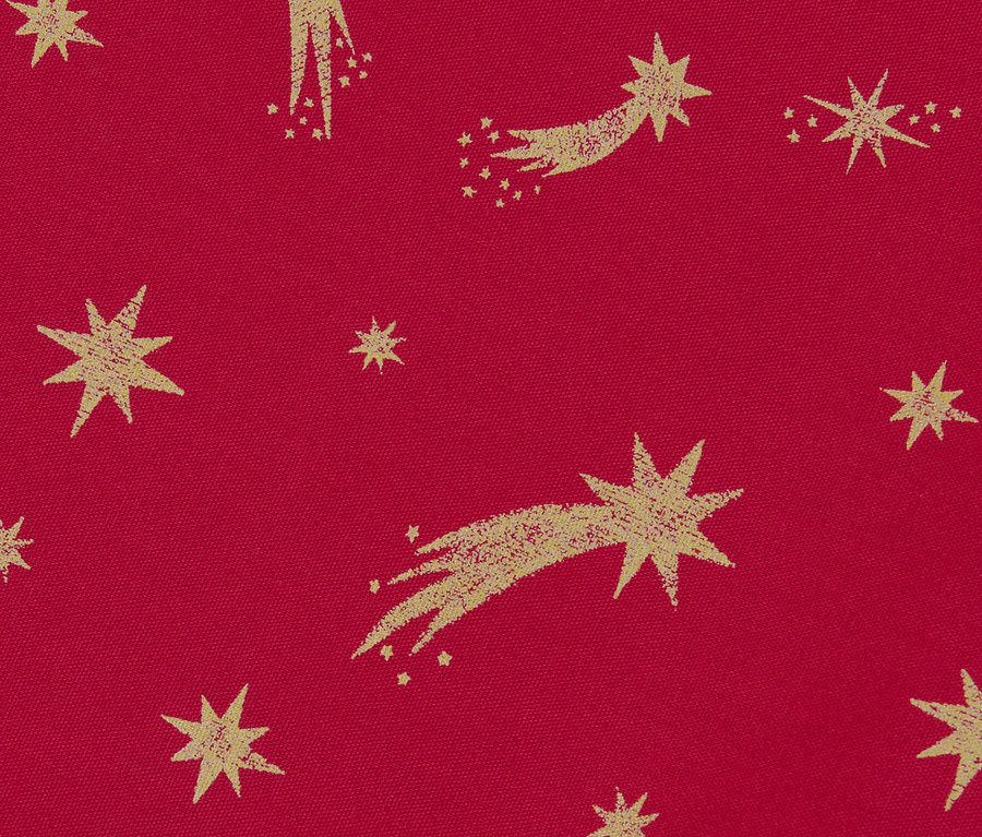 Detail bavlněného běhounu na stůl s potiskem zlatých hvězd na červeném pozadí.