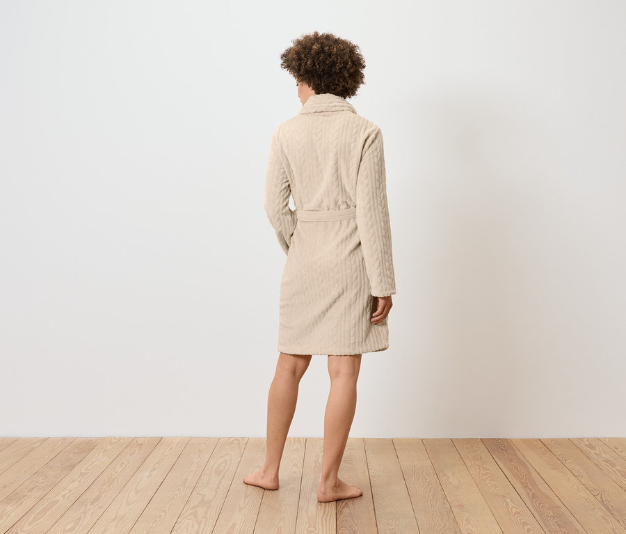 Žena zezadu v béžovém županu s copánkovým vzorem.