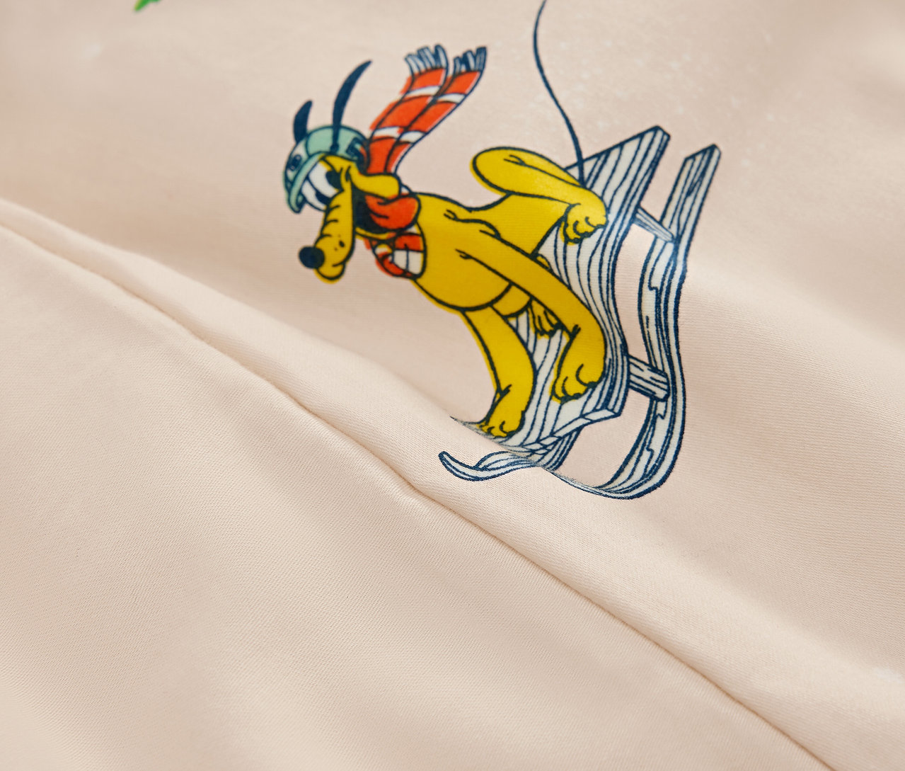 Kreslený obrázek žlutého psa s helmou a šálou na lyžích na béžovém pozadí.