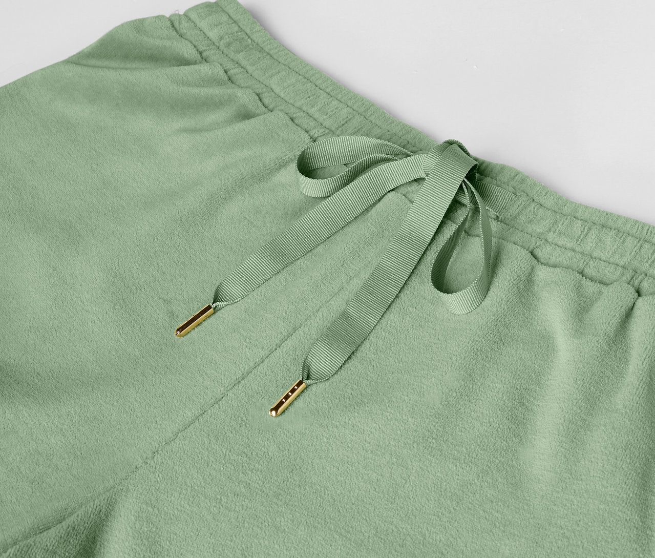 Detail světle zelených tepláků se stahovací šňůrkou.